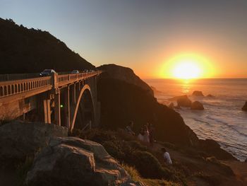 Arch bridge over sea against sky during sunset