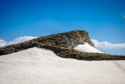 Low angle view of rocky mountain against blue sky