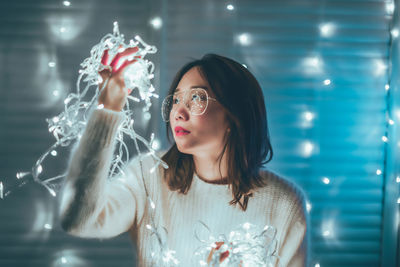 Portrait of young woman in illuminated glass