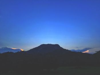 Scenic view of silhouette mountains against blue sky