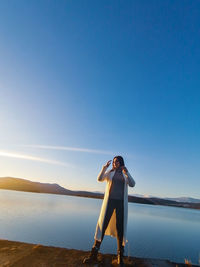 Man standing by sea against clear blue sky