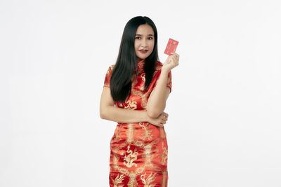 Portrait of beautiful young woman standing against white background