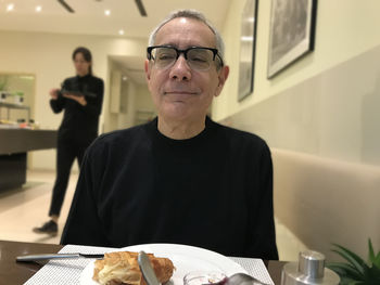 Portrait of man with food in plate on table at restaurant