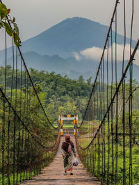 Rear view of man walking on footbridge