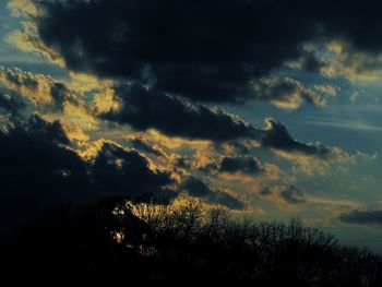 Low angle view of silhouette trees against dramatic sky