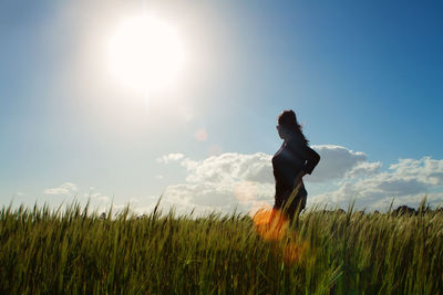 Side view of woman on field against bright sun