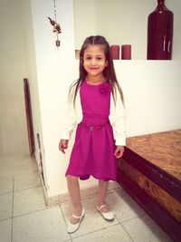 Portrait of smiling girl standing against wall