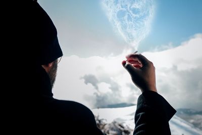 Rear view of man smoking cigarette against sky