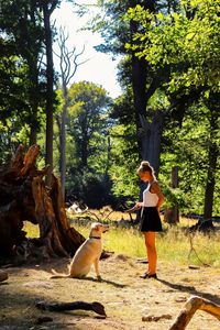 Side view of woman with dog standing in forest