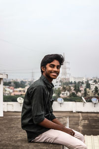 Portrait of young man smiling against sky