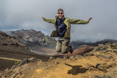 Full length of man with arms outstretched against sky