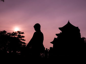 Low angle view of silhouette people at temple against sky during sunset