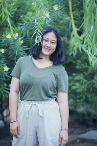 Portrait of teenage girl standing against tree outdoors