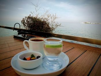 Coffee on table by sea against sky