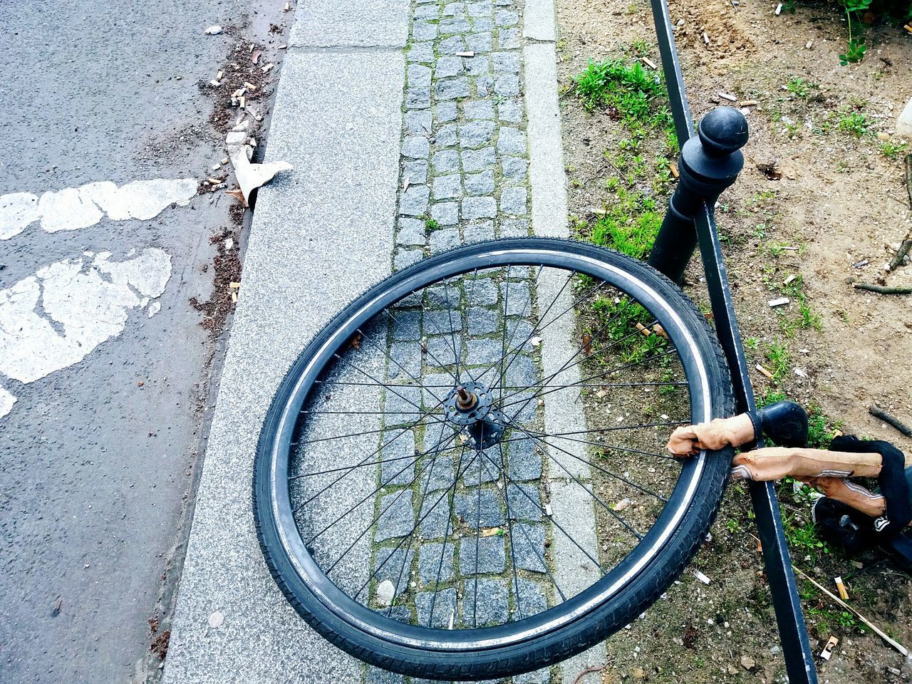 HIGH ANGLE VIEW OF BICYCLE WHEEL ON STREET WITH SHADOW