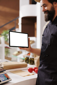 Side view of man using digital tablet while sitting on table