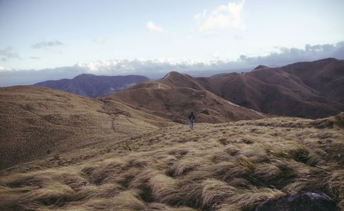 Man walking on landscape against sky