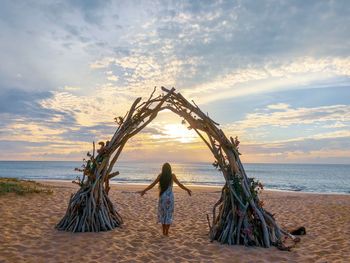 Rear view of woman on beach against sky