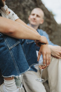 Young man holding wine in glass while sitting with friend