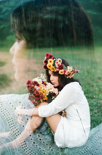 Close-up of flowers on woman sitting by plant