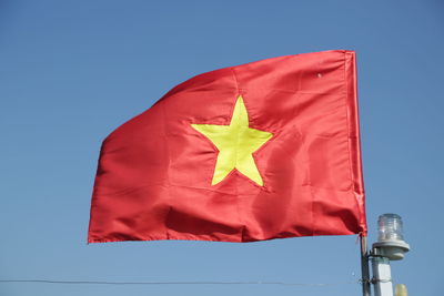 Low angle view of flag against blue sky