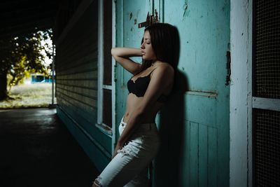 Side view of young woman standing against building