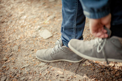 Low section of person adjusting shoe while standing on field