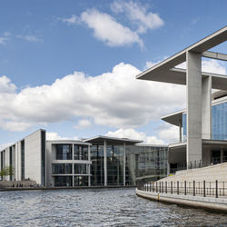 Buildings by river against sky in city