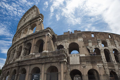 Low angle view of coliseum against cloudy sky