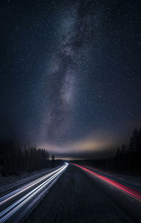 Light trails on road against clear sky at night