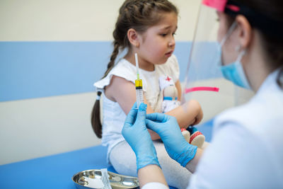 Child is afraid of injection. the doctor speaks with the girl and holds her hand. vaccine and protec