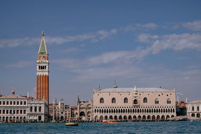 View of buildings by sea against cloudy sky