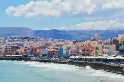 Cityscape by sea against sky