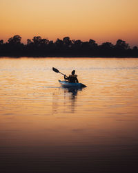 Silhouette man on boat on sea during sunset