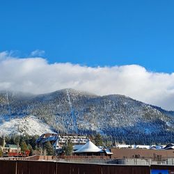 Panoramic view of buildings and mountains against blue sky