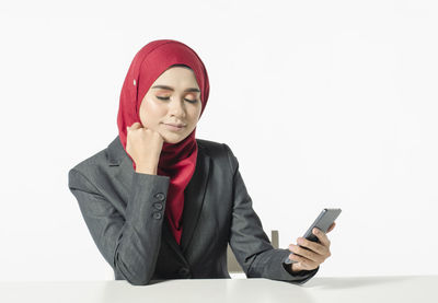 Young woman using mobile phone against white background