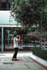 Full length of woman standing by tree against plants