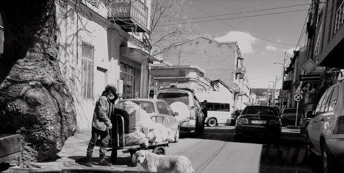 Rear view of people walking on street amidst buildings in city