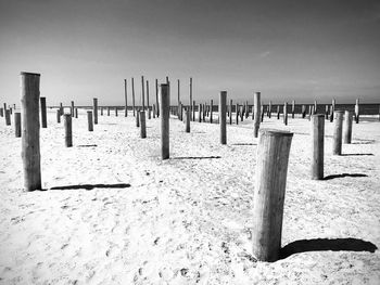 Wooden posts on beach against sky