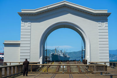 Rear view of man on building against clear blue sky