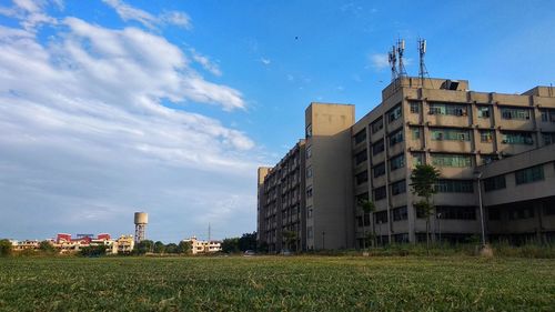 Buildings on field against blue sky
