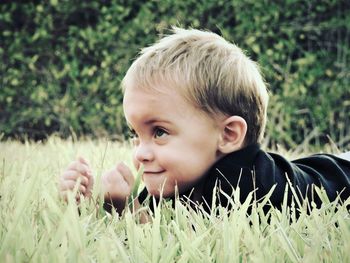 Close-up of cute smiling boy lying on grassy field