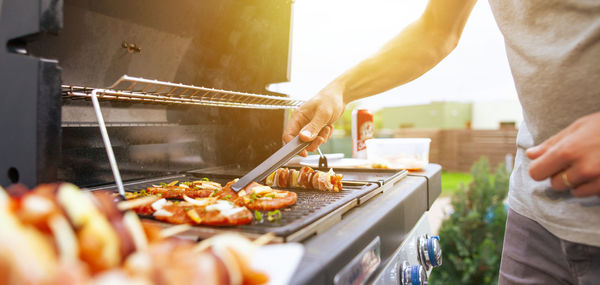 Midsection of man preparing food on barbecue grill