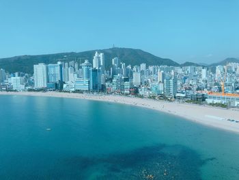 View of city by sea against clear blue sky