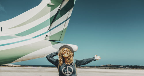 Rear view of woman with arms outstretched standing against sky