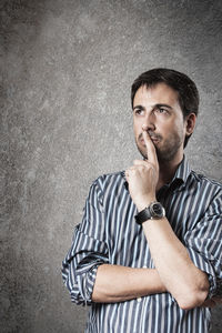 Portrait of young man standing against gray background