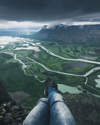 Low section of man sitting against river