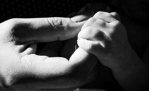 Close-up of man holding baby hand