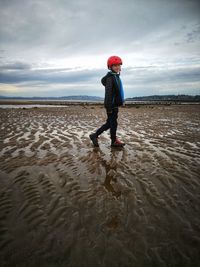 Boy walking on sand against sea at beach