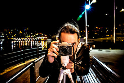 Portrait of man photographing against sky at night